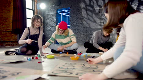 jóvenes activistas ambientales pintando carteles sentados en el suelo