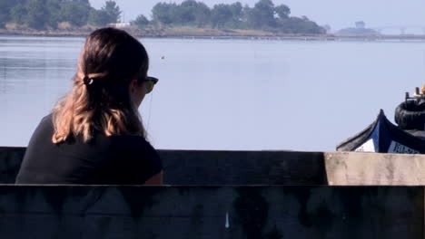 Woman-sitting-by-the-river,-calmly-observing-nature,-zen-moment