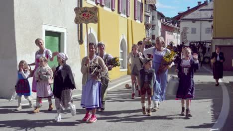 la brava part, participants of the annual end of summer parade walk through one of the town streets of folgaria, alpe cimbra, trentino, italy