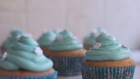 Close-up-slide-shot-of-bunch-of-cupcakes,-with-blue-icing-on-top