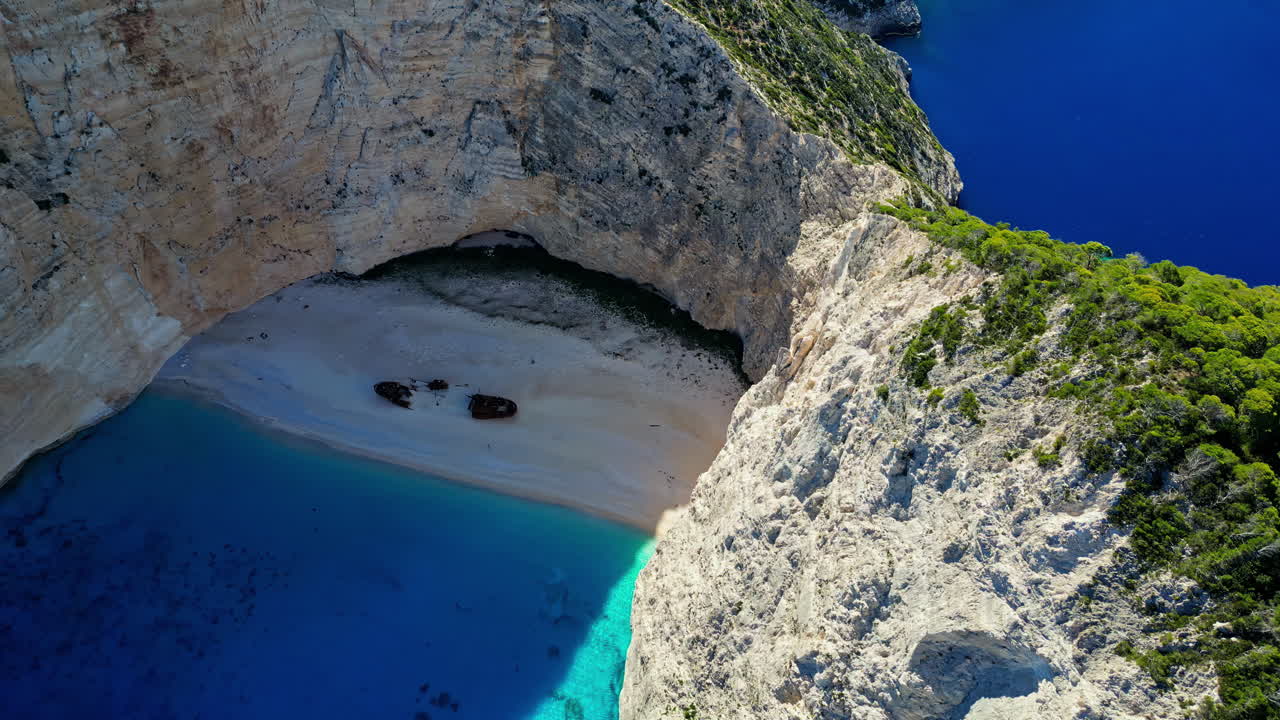 tomada de un dron de la playa de navagio en grecia en la sombra en un día soleado, amplia vista mirando hacia abajo