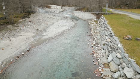 flying along the shallow river and above a beam bridge in cavergno, switzerland