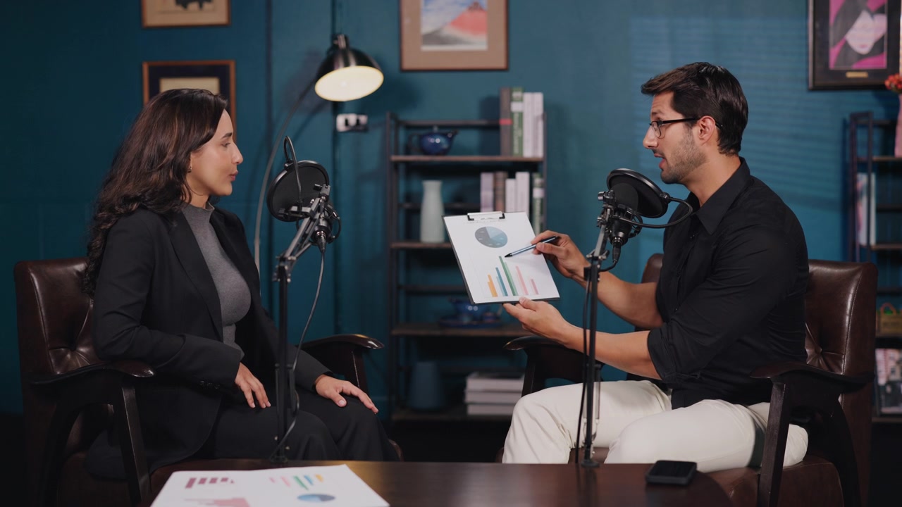 Conduttori professionisti di podcast aziendali che discutono di grafici finanziari in studio.