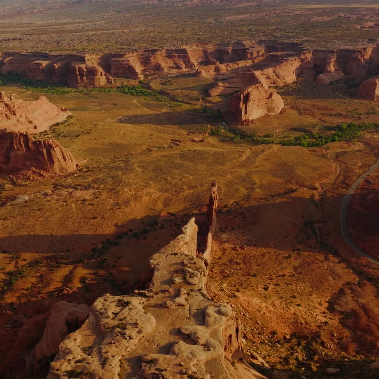 Deserted dry land with big stunning rocks of canyons. Sunlit panorama of Arches National Park from aerial perspective