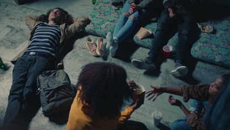 young group of friends relaxing on rooftop at night hanging out having casual conversation sharing snacks enjoying relaxing weekend party gathering