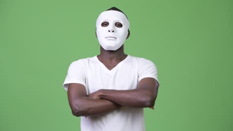 jonge afrikaanse man met een wit masker met gekruiste armen