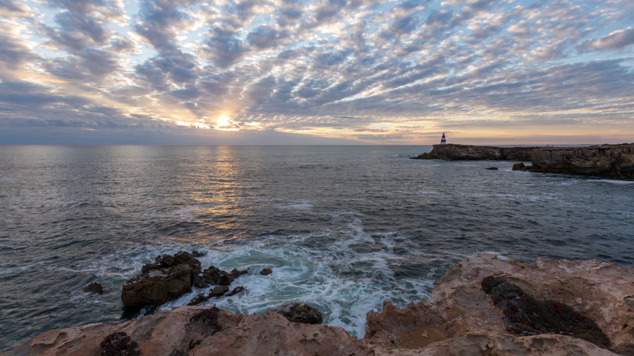lapso de tiempo del sol poniente que aparece entre una capa de nubes entrante sobre el océano en el obelisco de la túnica en el sur de australia, visto desde escarpados acantilados costeros de piedra caliza