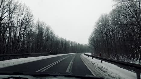 POV-vehicle-drive-countryside-wet-road-winter-scenery-snow-forest-bare-trees-dirty-window-gopro-point-of-view-car-travel-cloudy-sky