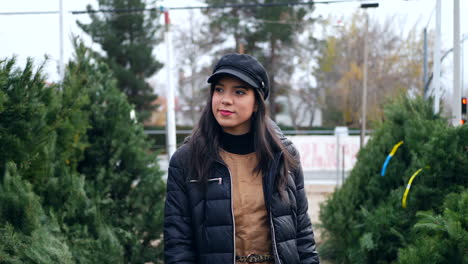 a beautiful woman in a happy holiday spirit smiling while shopping for festive douglas fir christmas trees