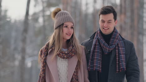 young married couple in love walking in the winter forest. a man and a woman look at each other laughing and smiling in slow motion. valentine's day love story.