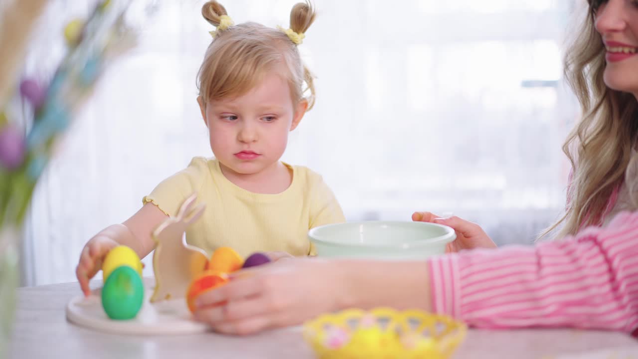 Bambina che gioca con uova di Pasqua colorate e una decorazione a forma di coniglio