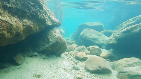 young-man-walking-in-clear-blue-water-at-day-from-front-angle