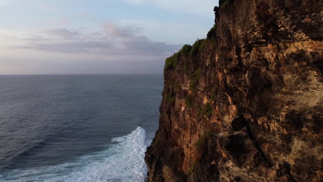 Drone-shot-flying-down-the-past-cliff-towards-the-ocean-in-Uluwatu,-Bali