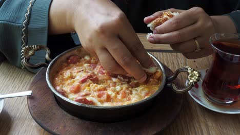 mujer comiendo menemen turco con pan y té