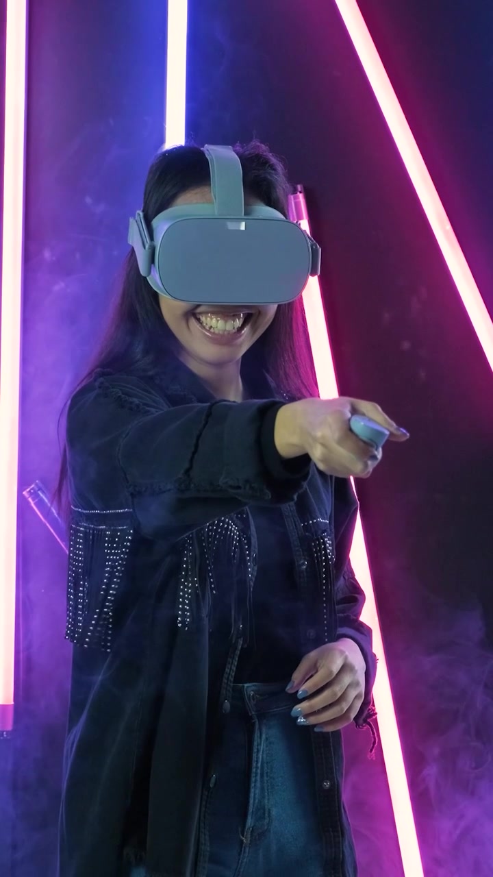 Giovane donna che gioca a un gioco di realtà virtuale in uno studio illuminato al neon