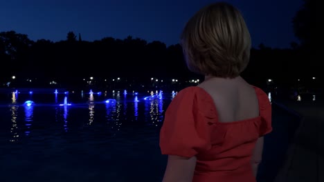 woman admiring illuminated fountain at night