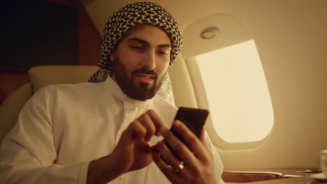 rich man looking smartphone on travel closeup. smiling arabian touching screen