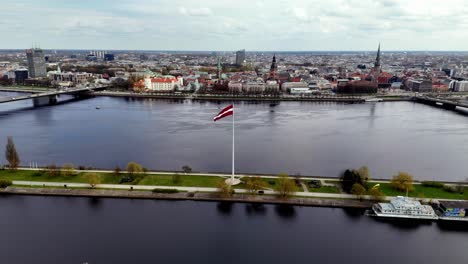 a massive flag flutters from an enormous flagpole in riga, latvia, europe - sideways shot