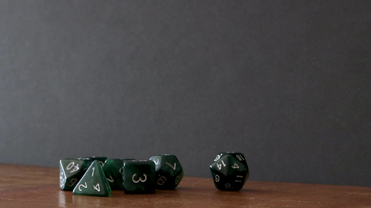 A pile of dice lay on a wooden table, the player first rolls a D20 on the table, picks it up and then rolls it through the frame from right to left until it dissapears out of the frame.