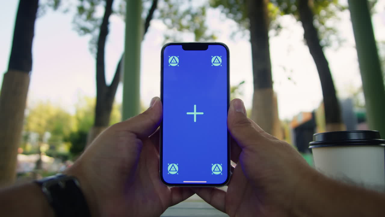 Young woman holding and swiping phone chroma key screen in the park in front of trees close-up. Girl with green screen on smart phone. Nature