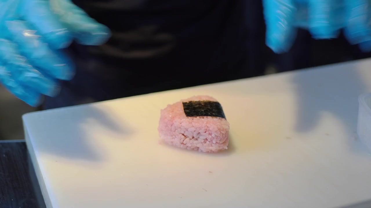 Chef che prepara onigiri di riso rosa con alga nori