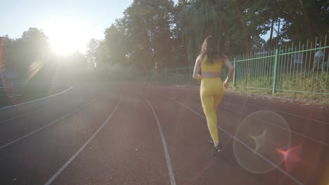 woman running on outdoor track in yellow sportswear