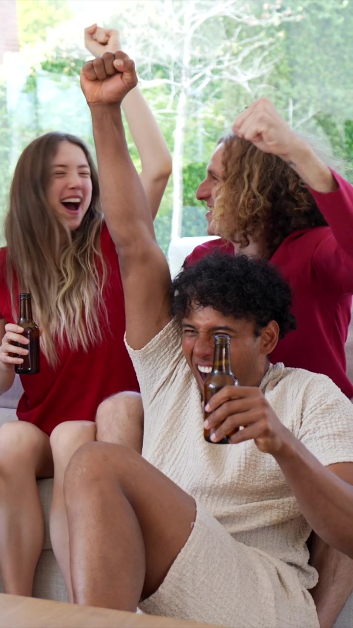 Giovani amici entusiasti che brindano e festeggiano con birra a casa