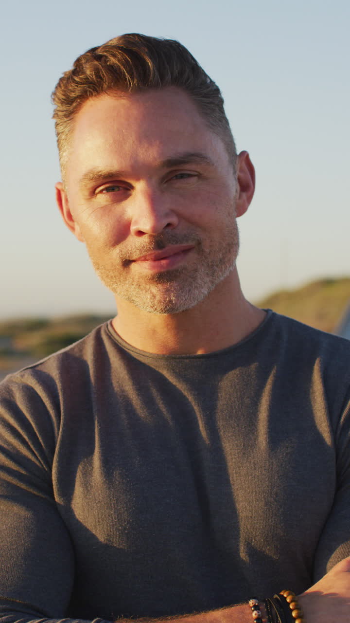 retrato de video vertical de un hombre caucásico sonriente en la playa, disfrutando del tiempo libre