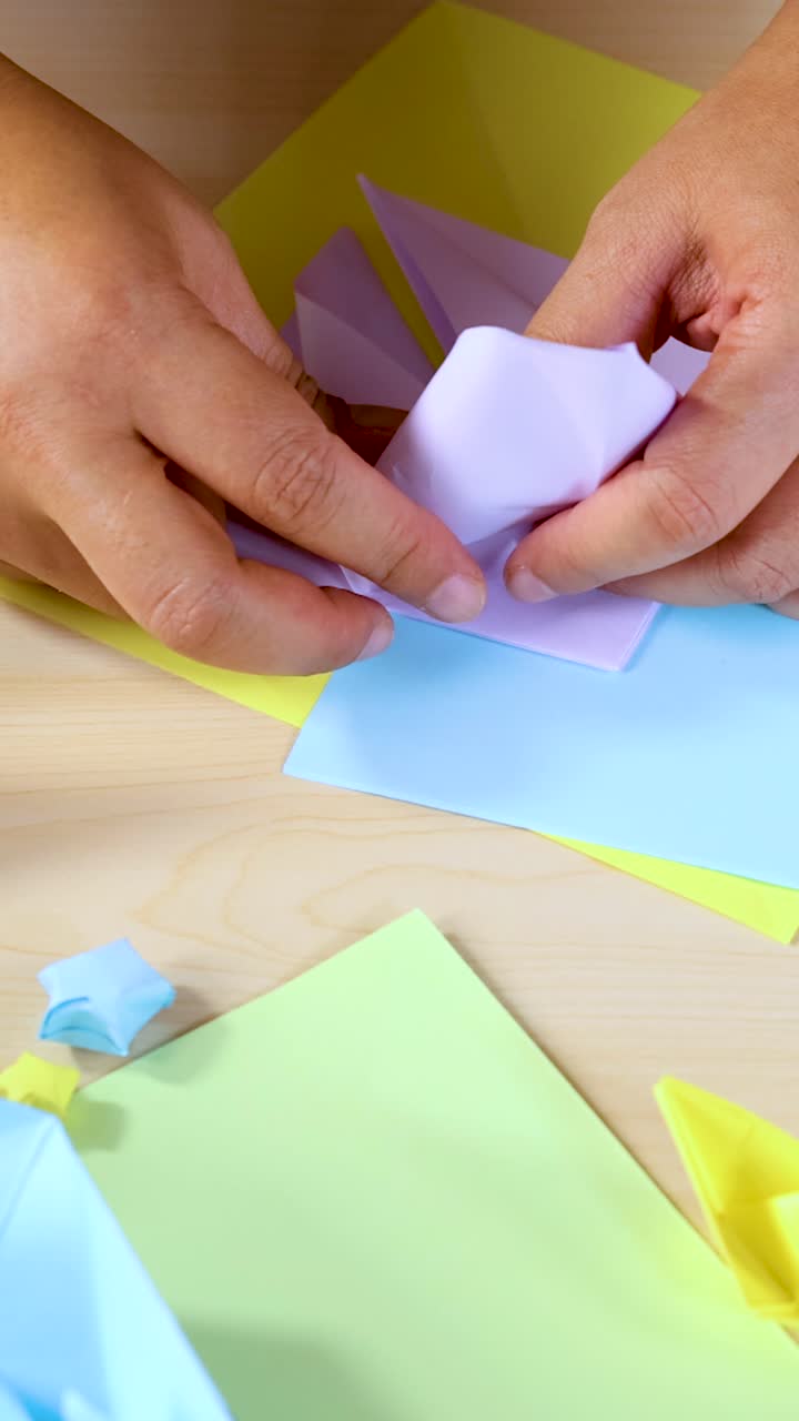 Mani adulte piegano carta pastello in una barca di origami su un tavolo di legno, illuminazione brillante