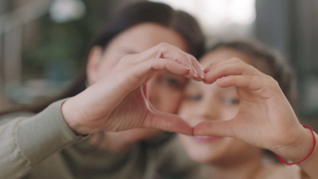 Mother and Daughter Making Heart Shape with Hands