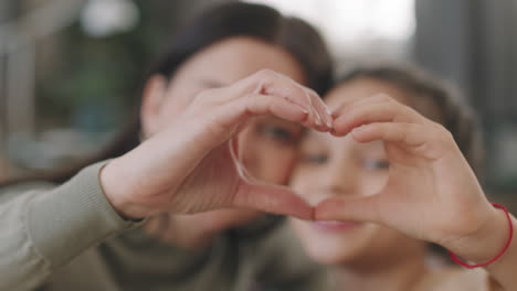 mother and daughter making heart shape with hands