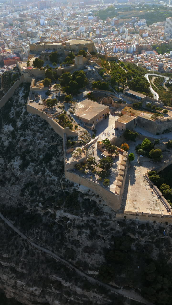 Aerial drone view of the Santa Barbara Castle on the coast of Alicante, Spain with the city on the background. Vertical