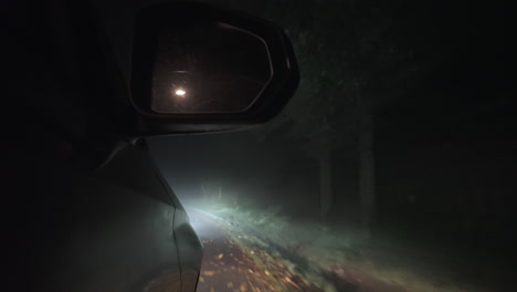 car driving at night, side low front view of mirror and countryside road lost in fog