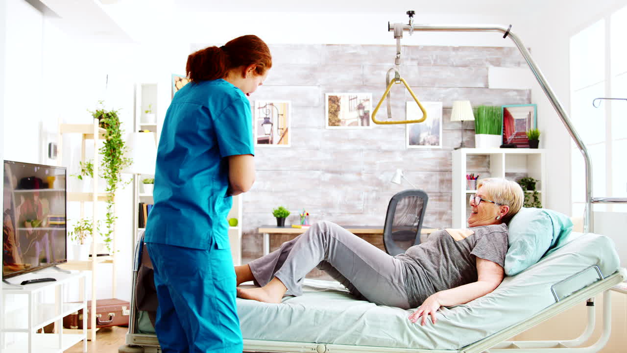 enfermera ayudando a una anciana a acostarse y cubriéndola con una manta