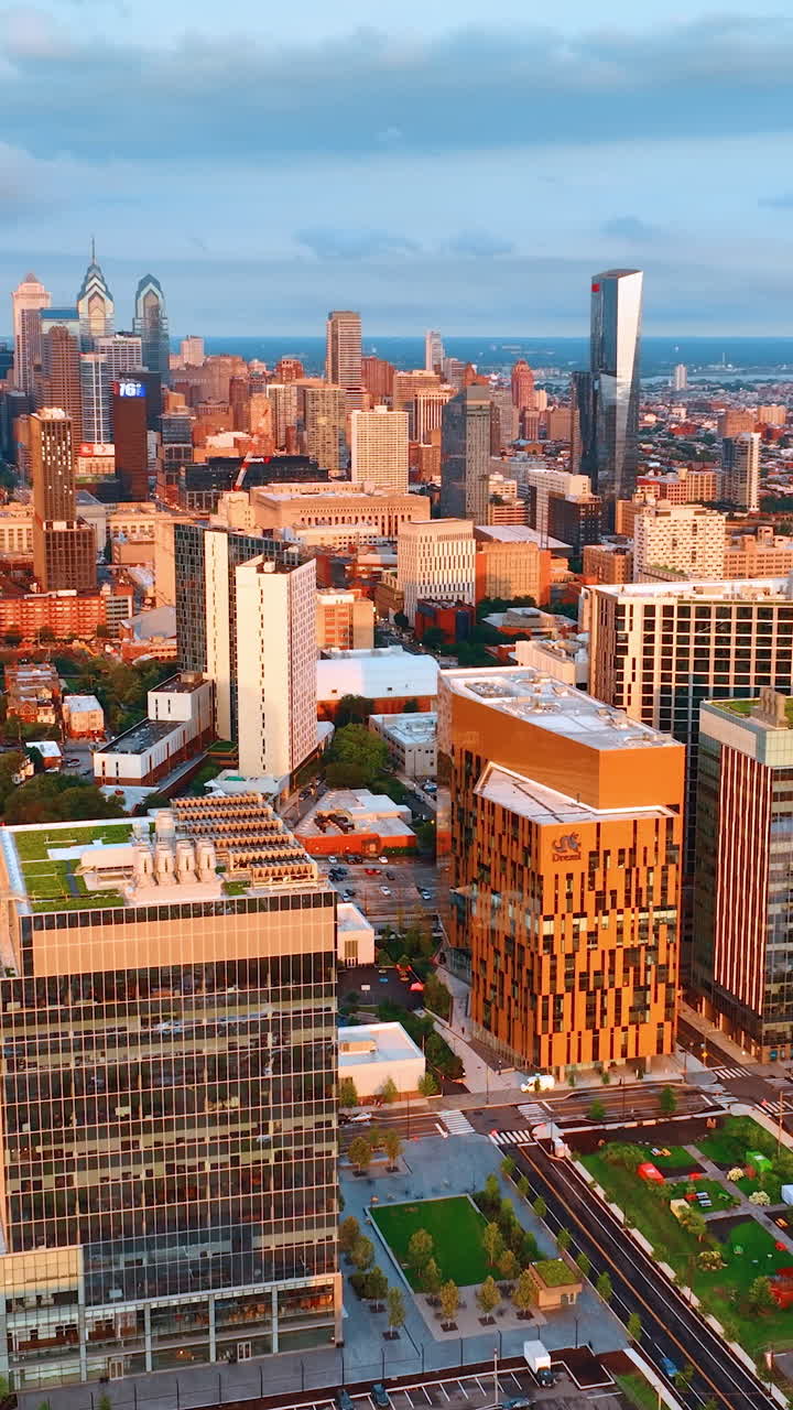 Buildings of Philadelphia downtown in the rays of setting sun. Bright cityscape of the city with skyscraper complex in the centre. Top view. Vertical video