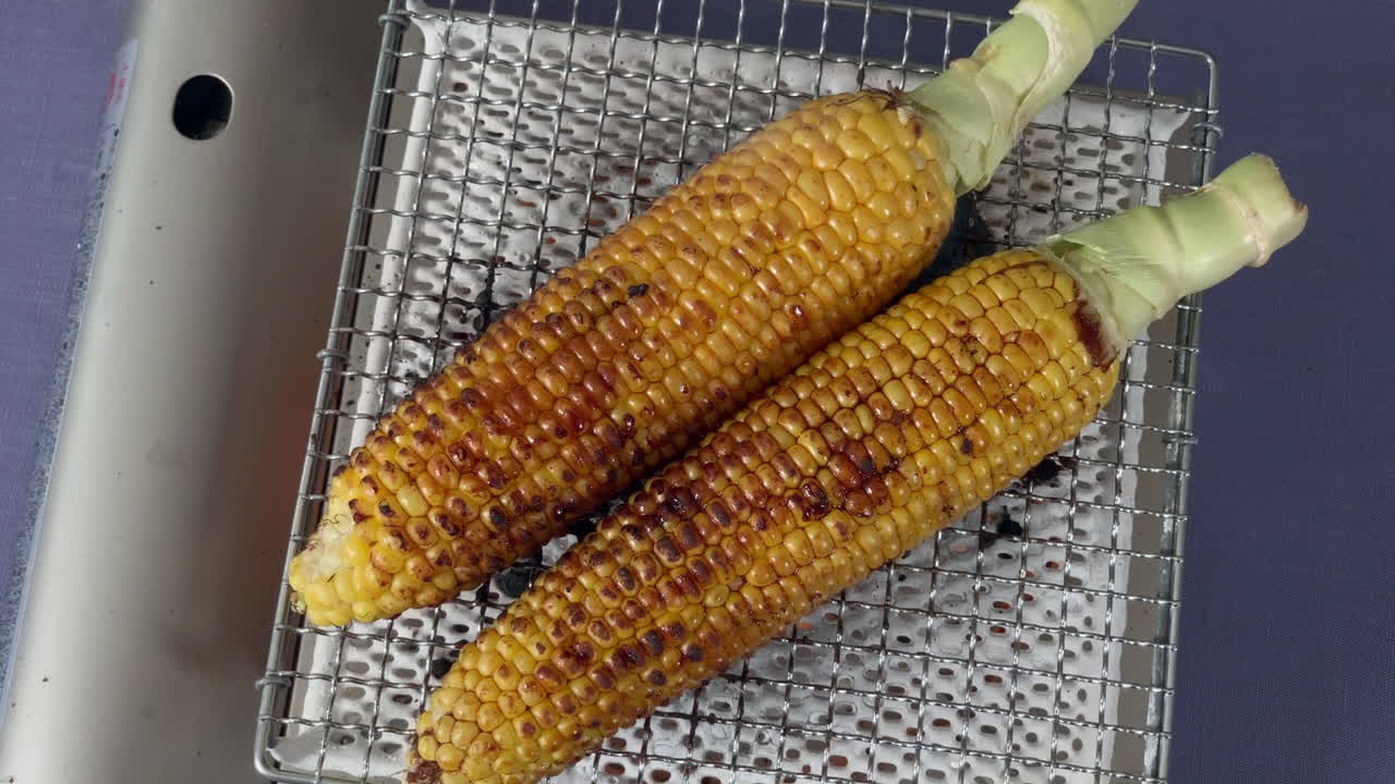 una chef japonesa pone shoyu en maíz a la parrilla en la cocina de su casa, tokio, japón
