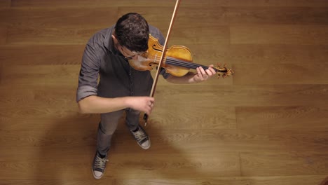 un luthier barbudo adulto tocando un violín hecho a mano