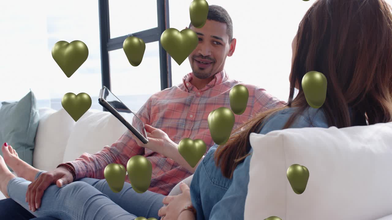 Man showing tablet, woman taking it then phone, tapping, sharing with green hearts over faces, tech