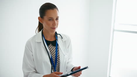 Female-Doctor-With-Digital-Tablet-Checking-Patient-Notes-On-Stairs-In-Hospital