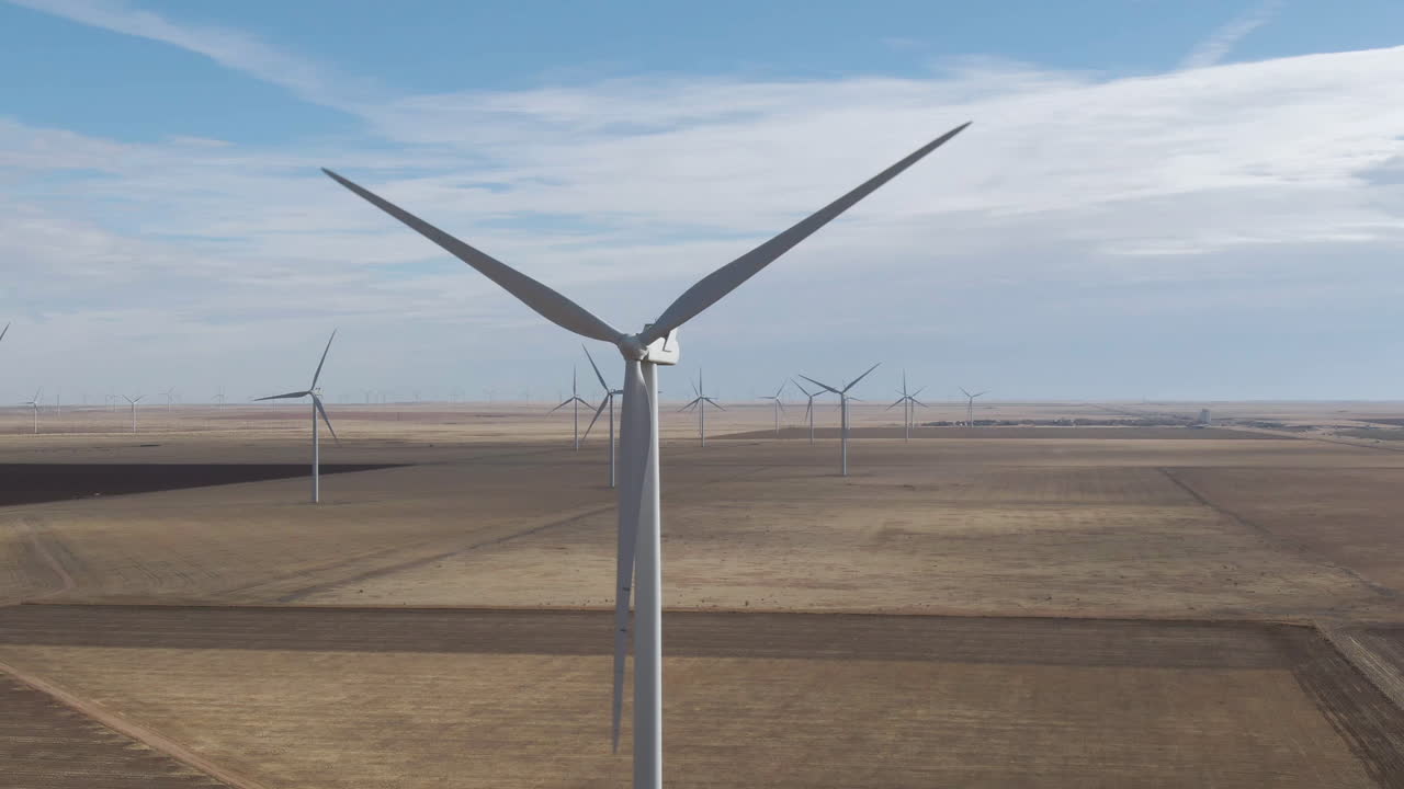 4k close up of large wind turbine spinning over plains in North Texas, USA amid a mass wind farm