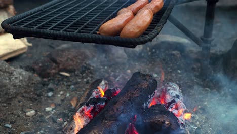 sausages getting grilled over a soldering open fire flame grill outdoors, with copy space