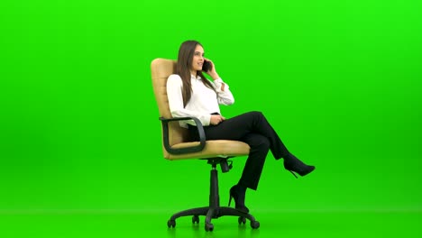 the happy woman phones on the office chair on the green background