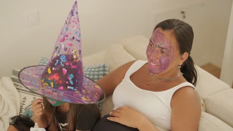 pregnant mother relaxing with daughter in witch costume