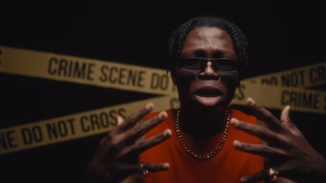 Black Rapper Performing Hip-Hop Song in front of Crime Scene Tape at Night