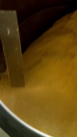 centrifuge mechanism rotating and mixing yellow stuff. maize snacks production at food factory. close up. vertical video