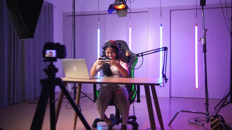 Excited Asian Kid Girl Playing Video Game With Mobile Phone While Live Stream, Professional Light Equipment
