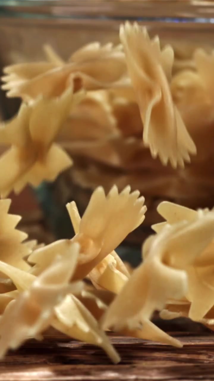 Farfalle secche che cadono al rallentatore su una superficie di legno