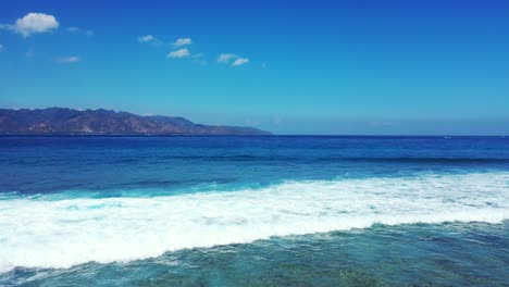 foamy waves of turquoise ocean waters rolling on the sandy coast