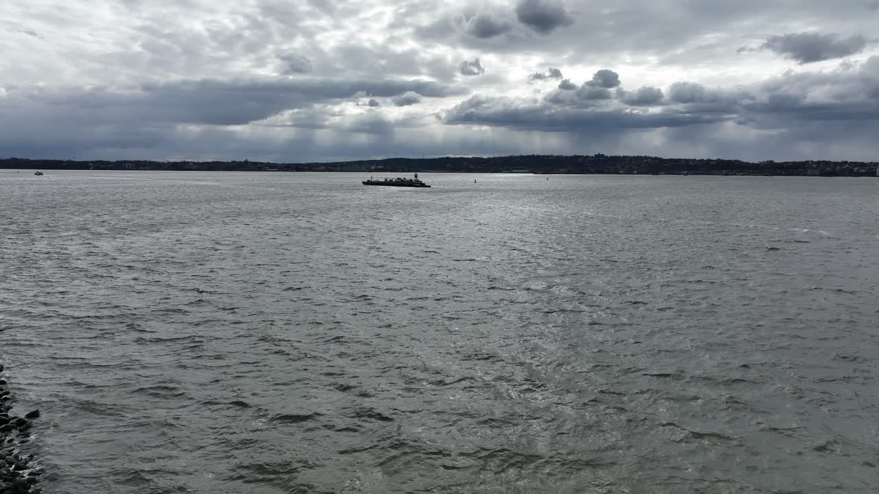 구름이 많은 날에 뉴욕의 어퍼 베이에서 항해하는 바지와 페리의 공중 풍경