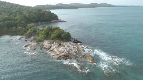 drone flight over a rocky outcrop, small fishing boat and ocean